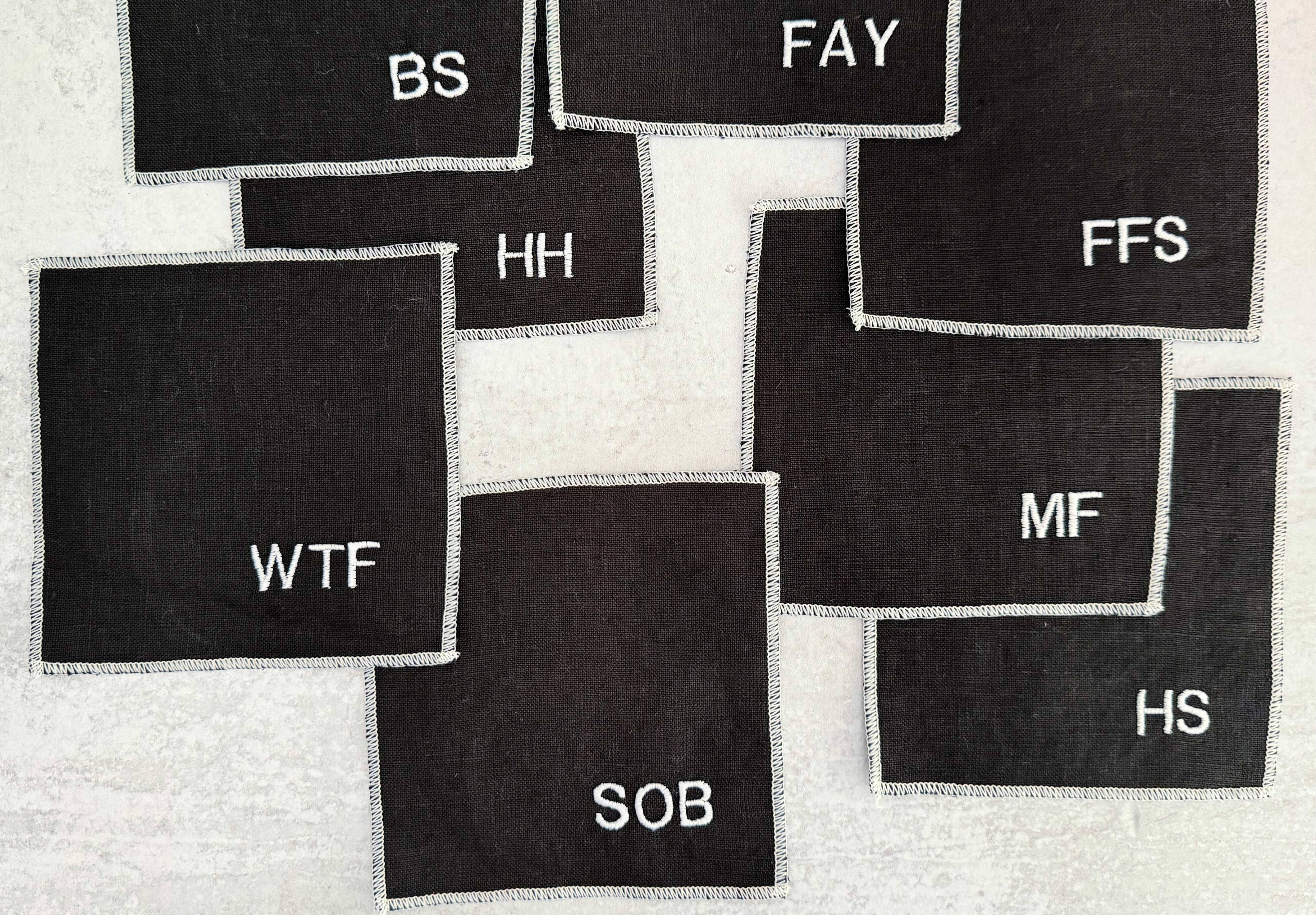 Black fabric patches with various text labels on a textured white background