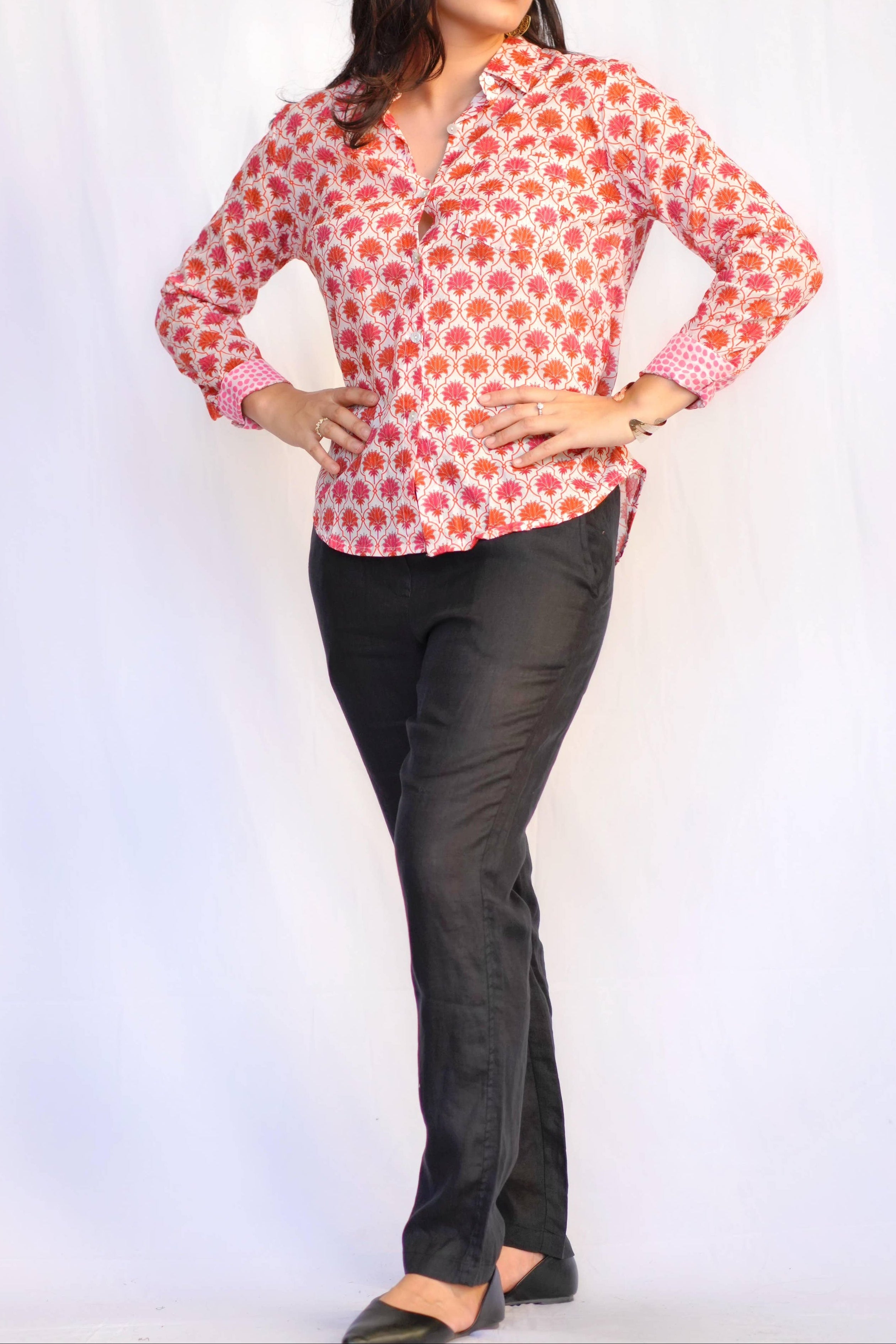 Woman wearing a red floral blouse and black pants on a white background