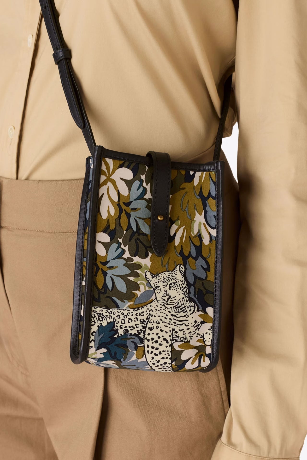 Person wearing a beige outfit with a floral-patterned crossbody bag featuring a leopard design.