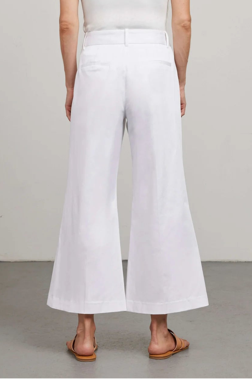 Person wearing a white sleeveless top and wide-leg pants on a plain background