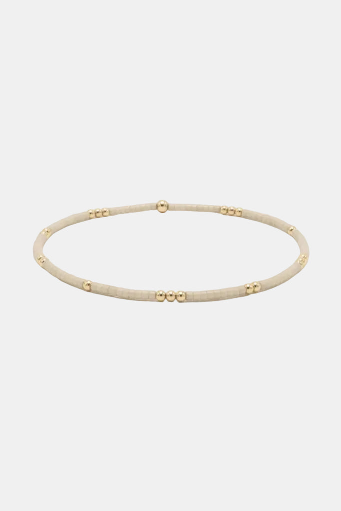 Beige bracelet with gold beads on a white background