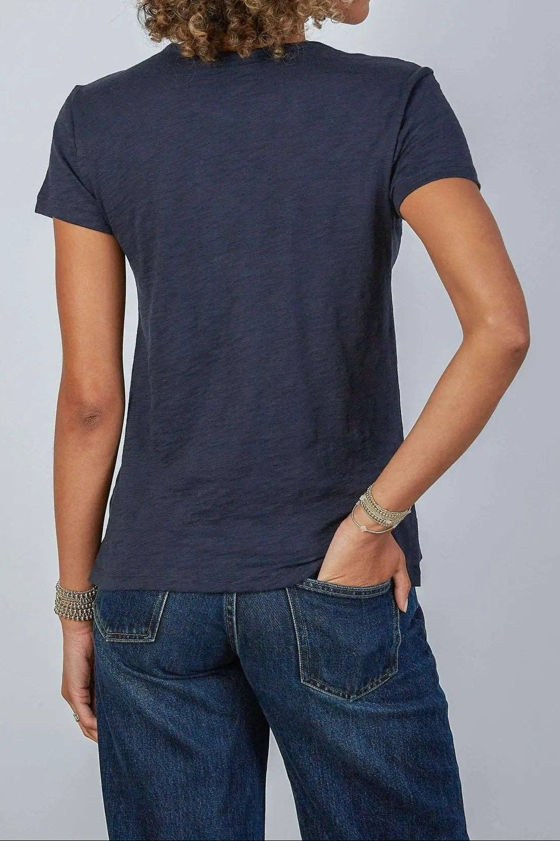 Person wearing a navy blue t-shirt and jeans on a plain background
