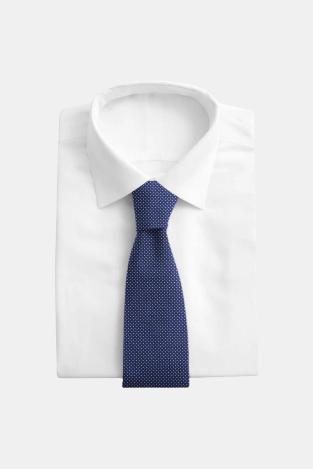 A navy blue necktie with a small white dot pattern, neatly tied and displayed on a folded white dress shirt against a light gray background.