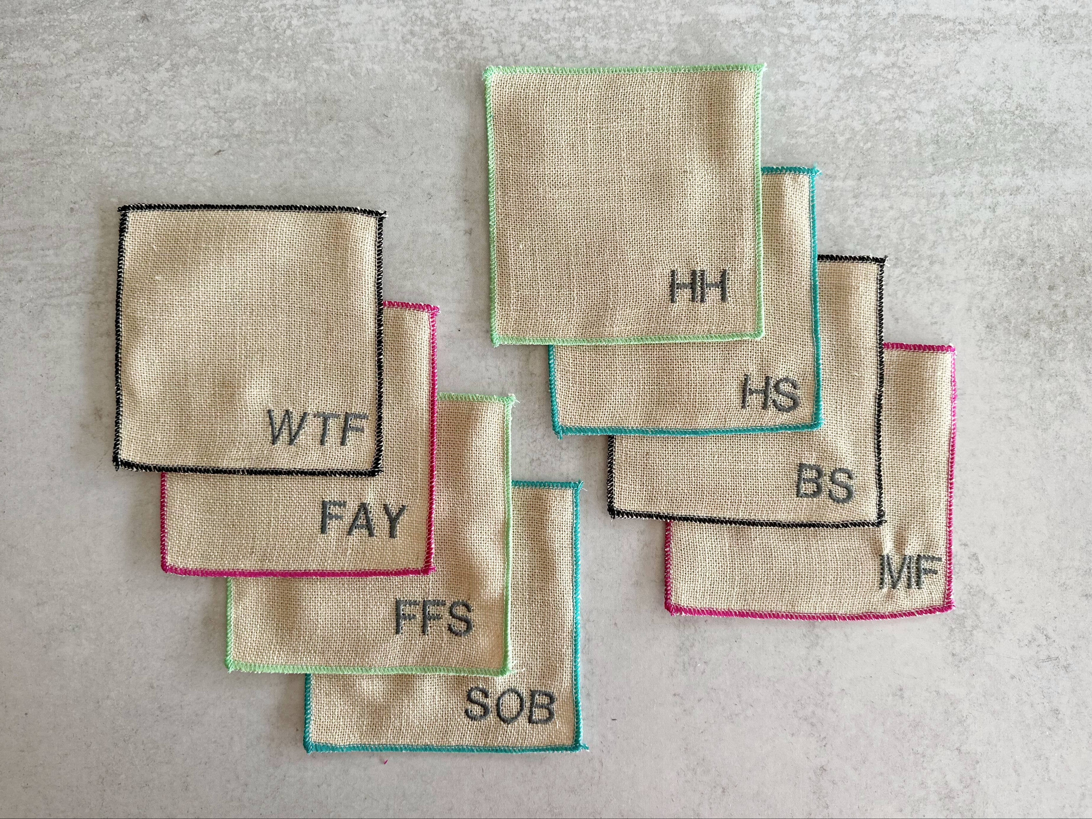 Set of embroidered fabric squares with various text on a gray surface