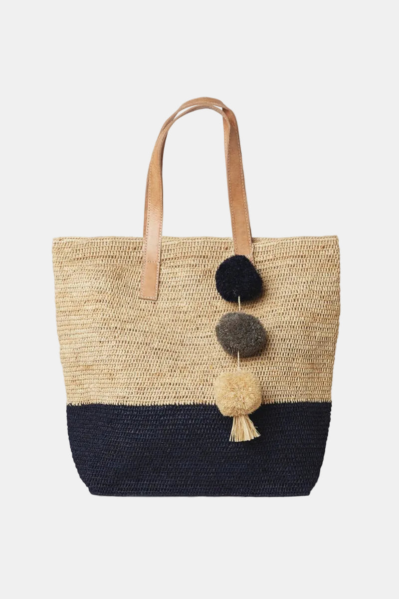 Woven tote bag with pom-pom decorations on a white background