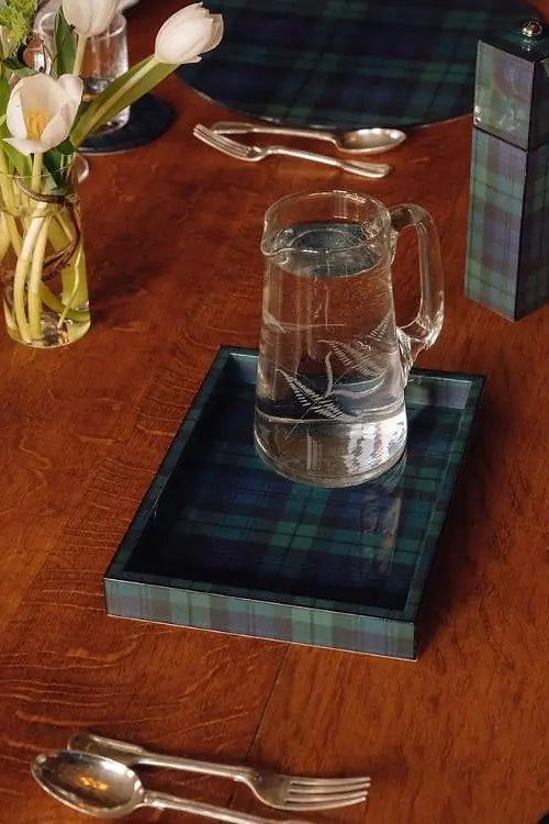 Clear glass pitcher on a plaid tray with a wooden table setting