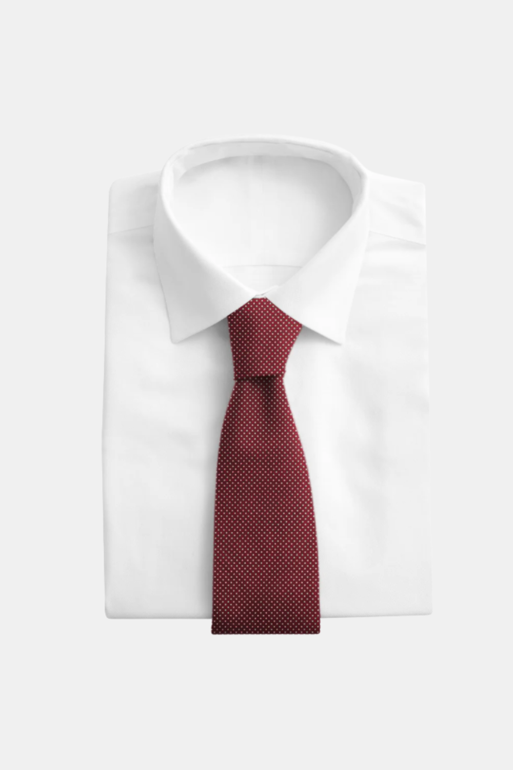 A folded white dress shirt with a red micro-dot patterned necktie, presented on a light gray background.