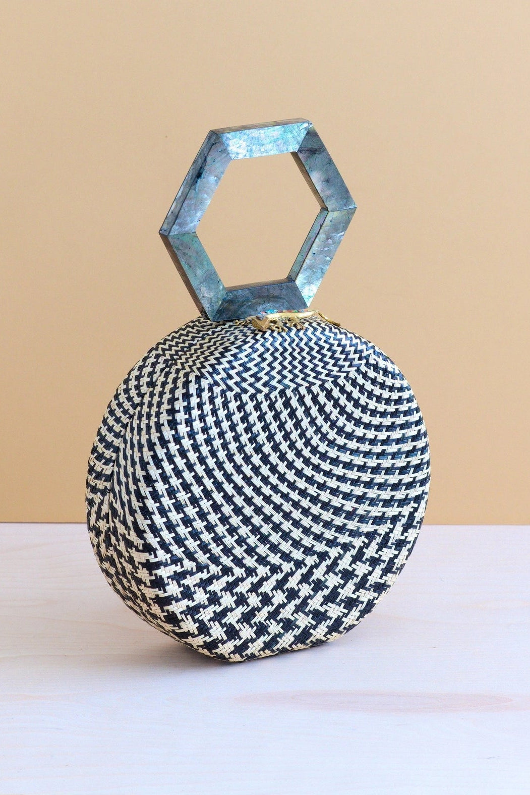 Woven handbag with geometric handle on a beige background
