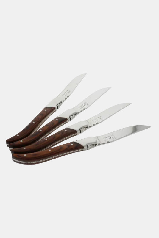Set of four steak knives with wooden handles on a white background