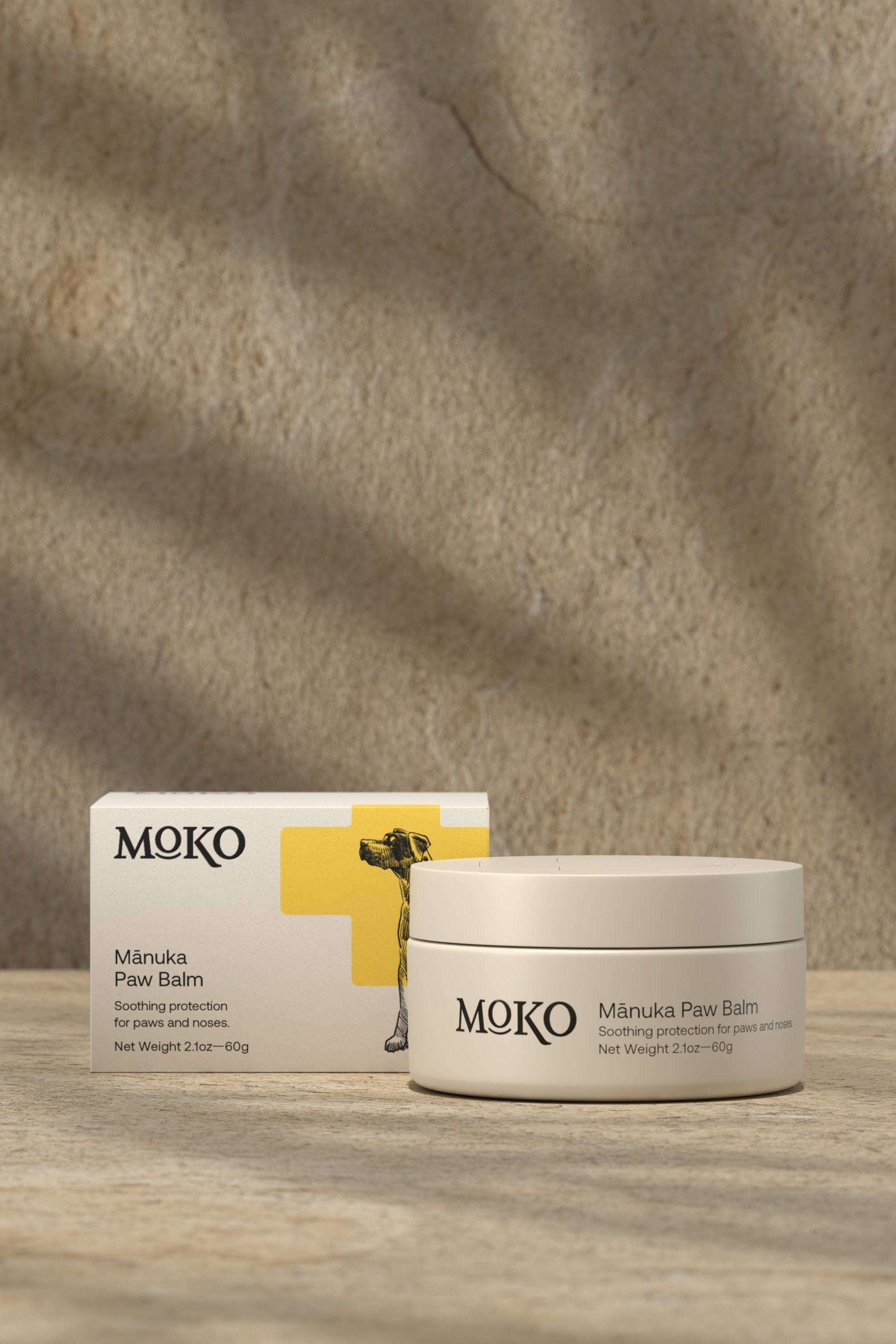 MOKO Manuka Paw Balm jar and box on a wooden surface with a stone wall background
