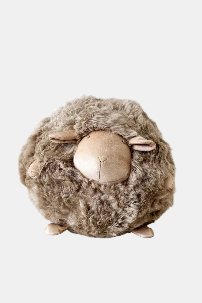 Plush sheep toy on a white surface with a light background