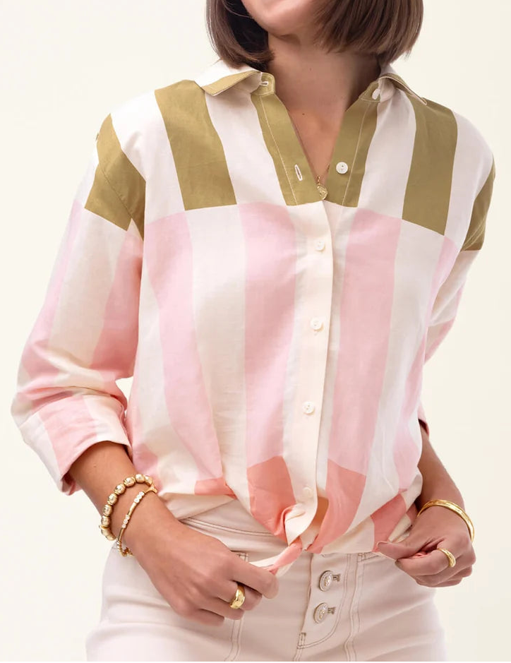 Woman wearing a pink and green striped shirt on a plain background