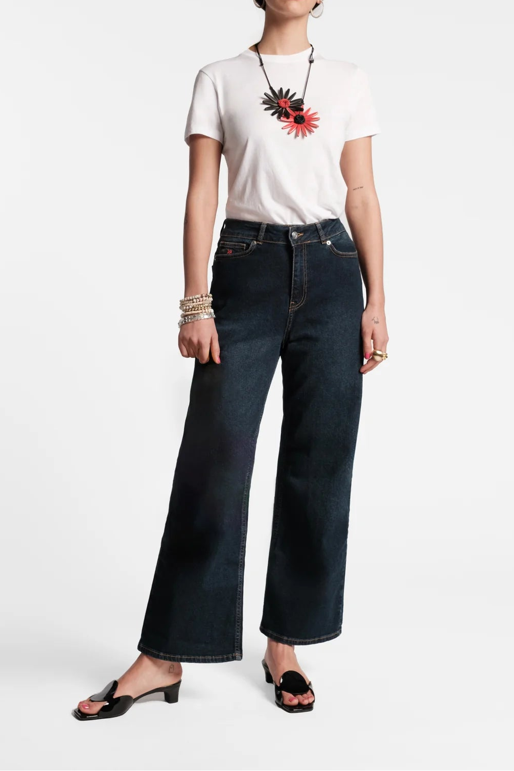 Woman wearing a white t-shirt with a colorful design and dark blue jeans on a white background