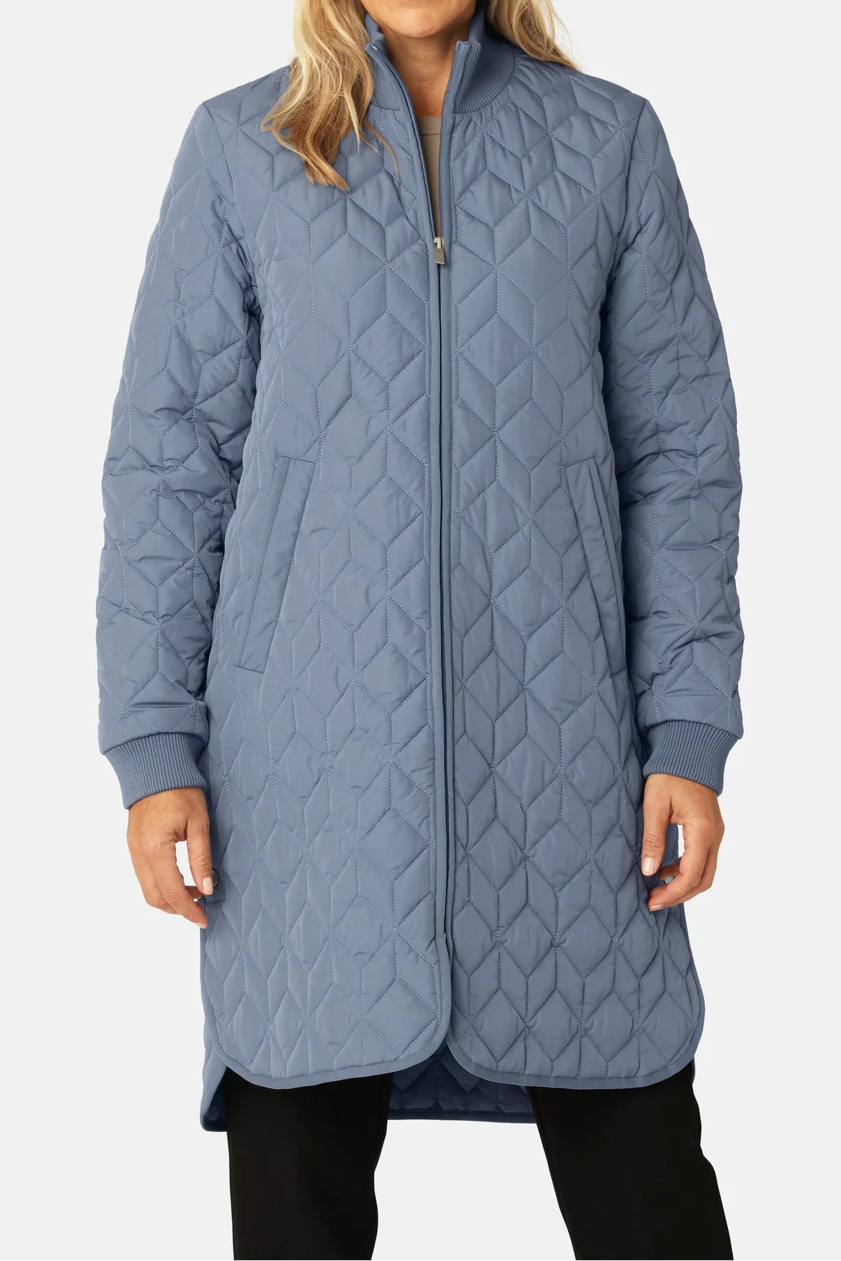 Woman wearing a long quilted blue jacket on a white background