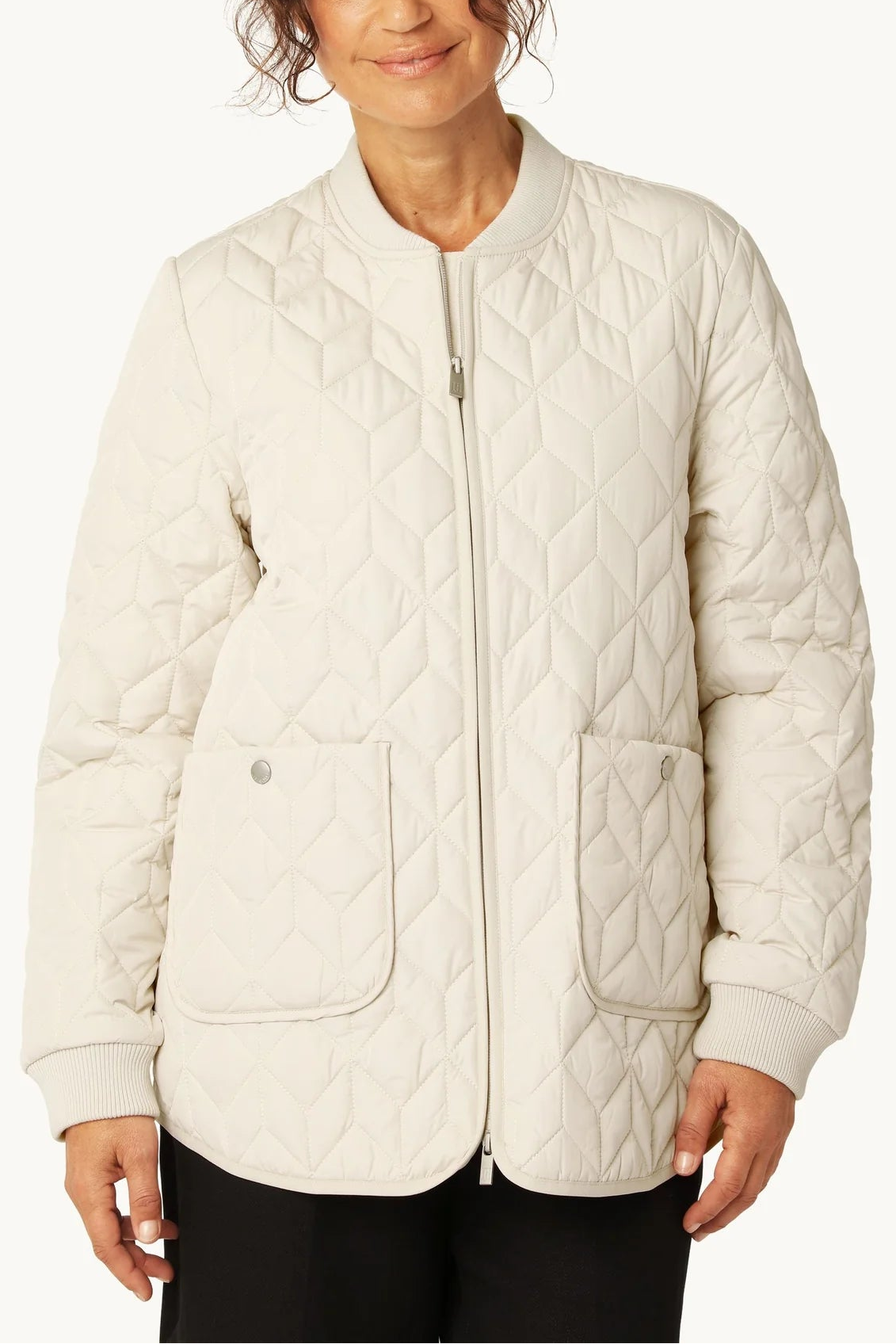 Woman wearing a quilted beige jacket on a white background