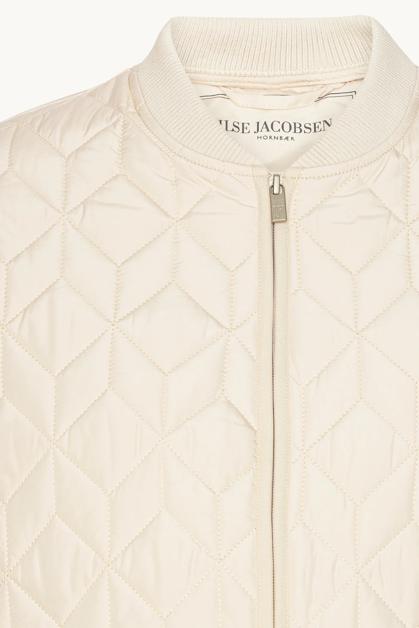 Close-up of a quilted cream zip-up jacket by Else Jacobsen, showing the diamond-quilted pattern, ribbed collar, and silver zipper.