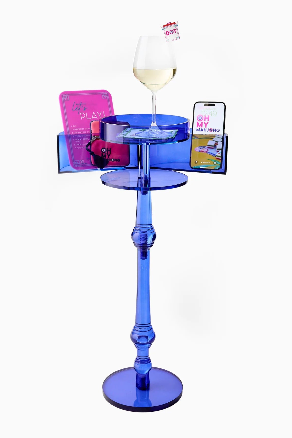 Blue glass table with a glass of wine, magazine, and phone on a white background