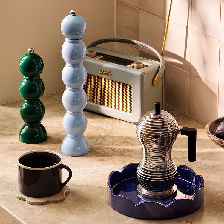 Kitchen scene with a vintage-style radio, ceramic salt and pepper shakers, and a coffee maker on a tiled floor.