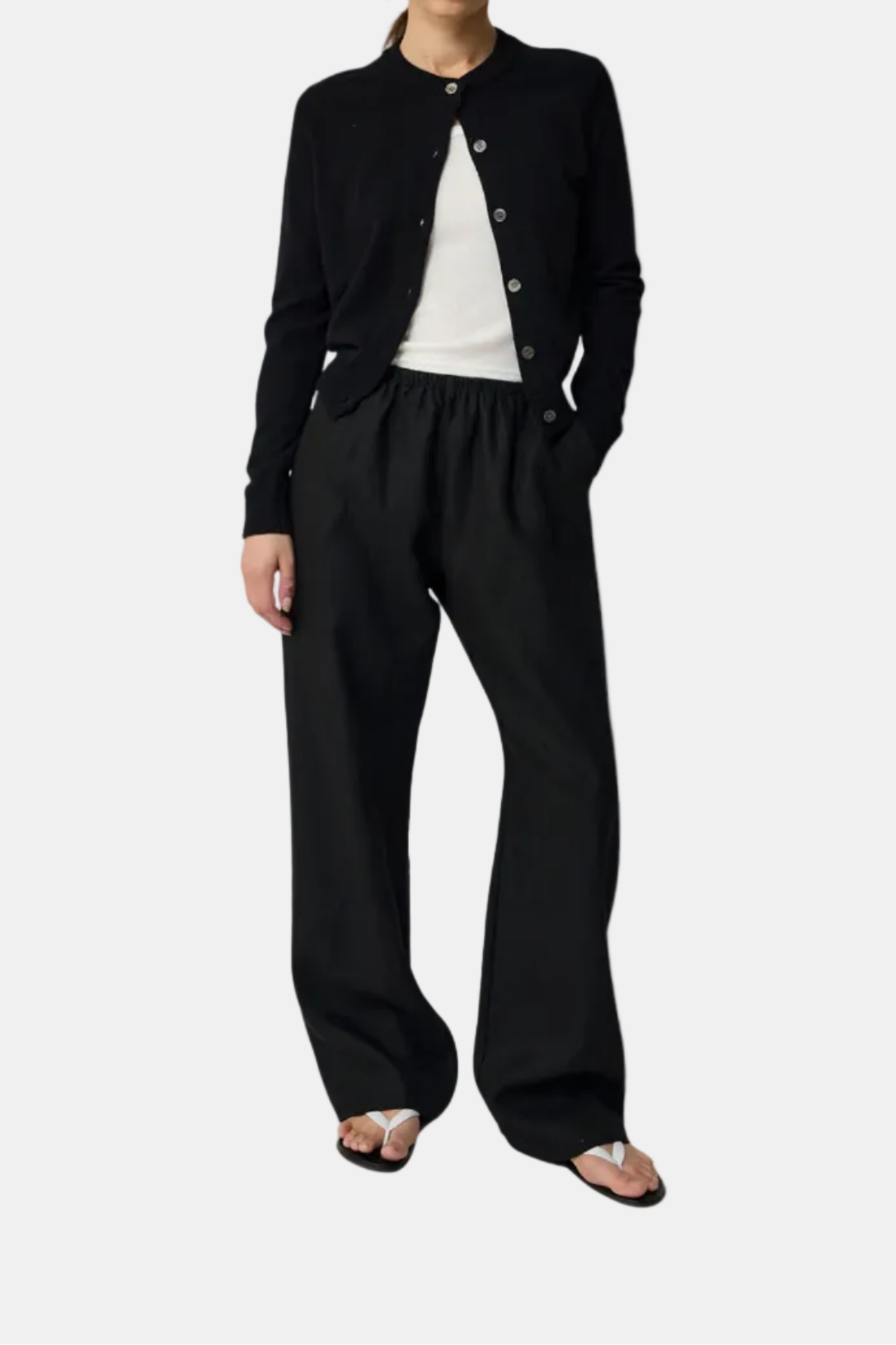 Woman wearing a black cardigan and pants on a white background