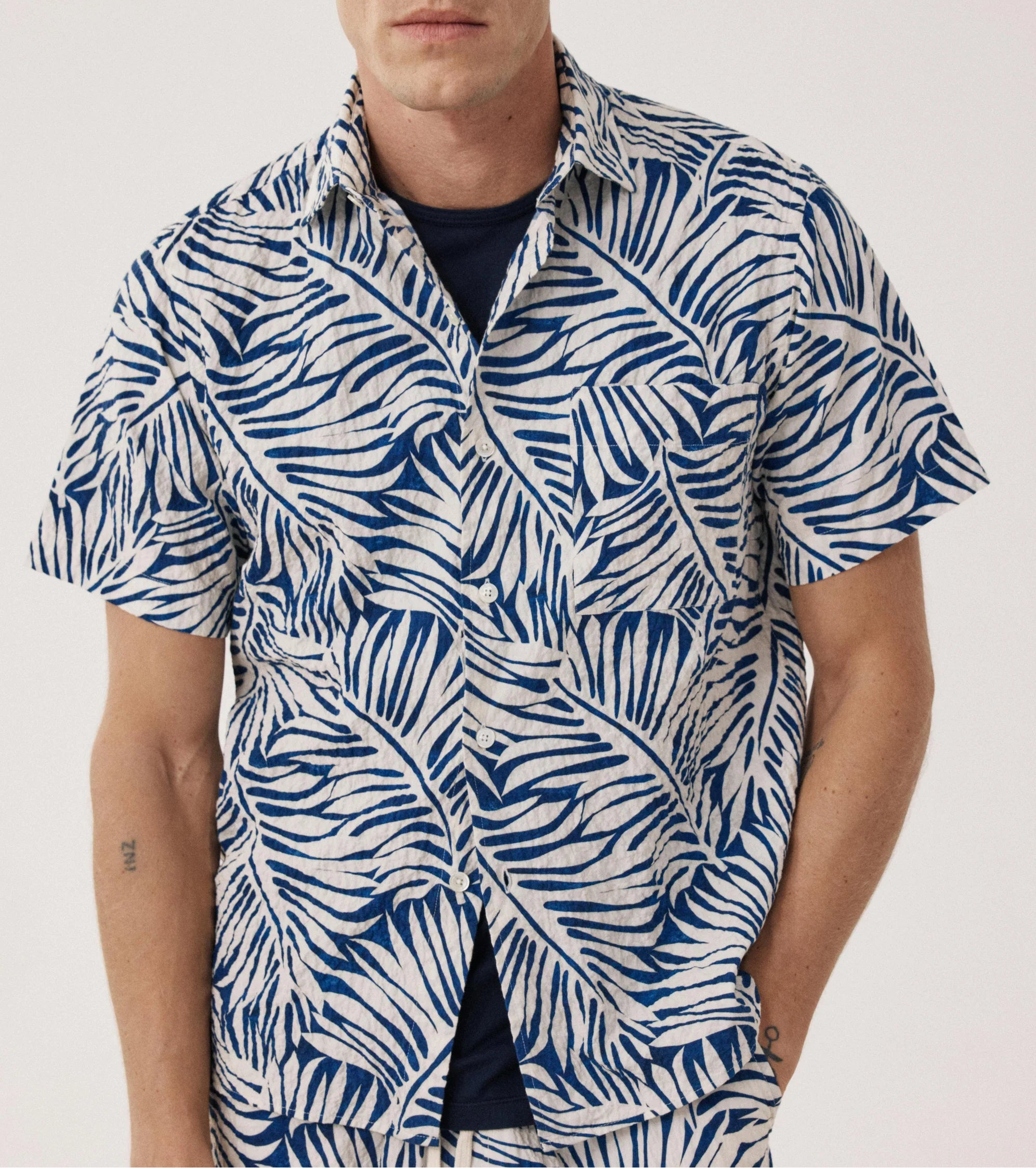 Man wearing a blue and white patterned shirt on a plain background