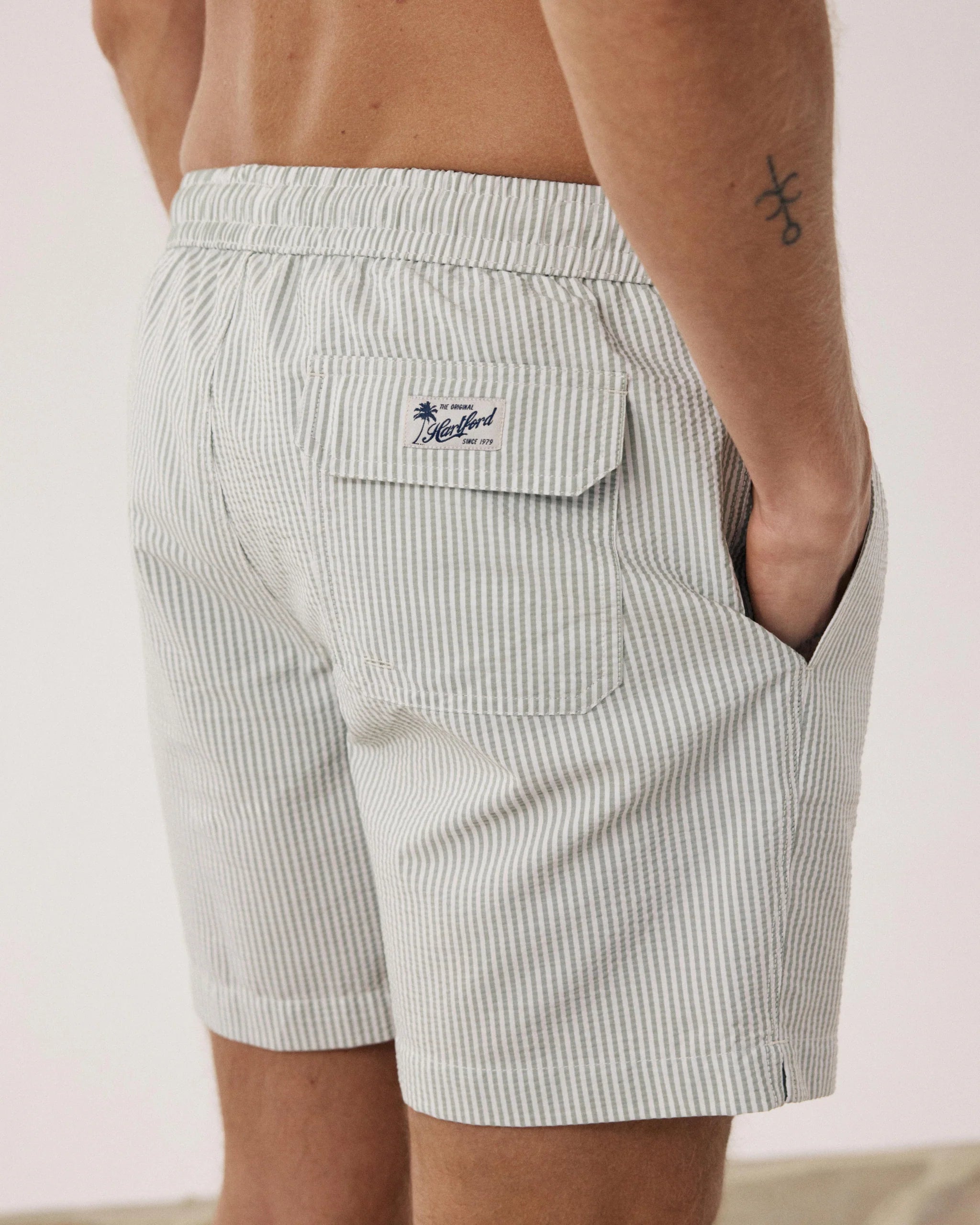 Person wearing light gray striped shorts with a brand logo on a neutral background