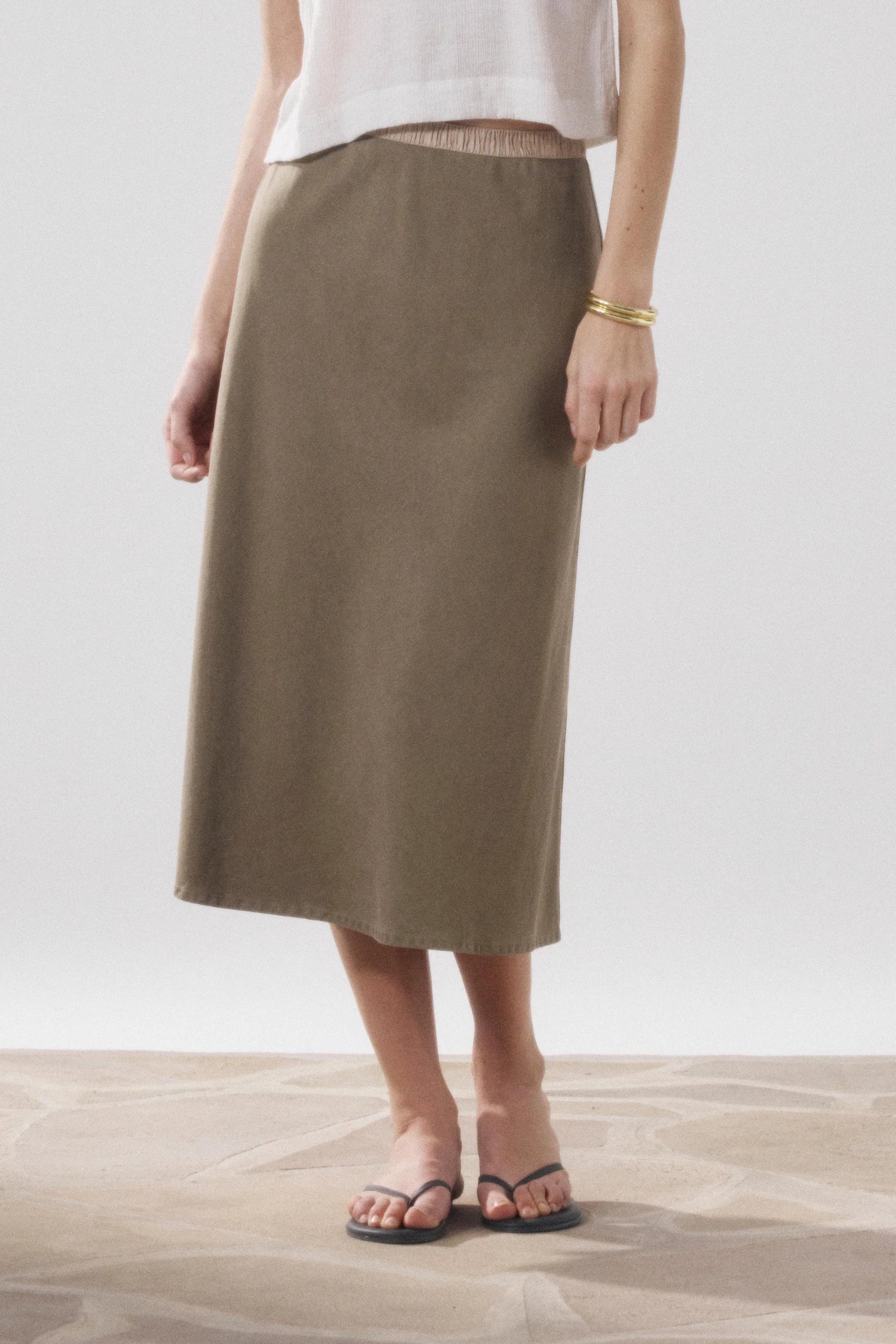 Person wearing a brown skirt and white top on a plain background