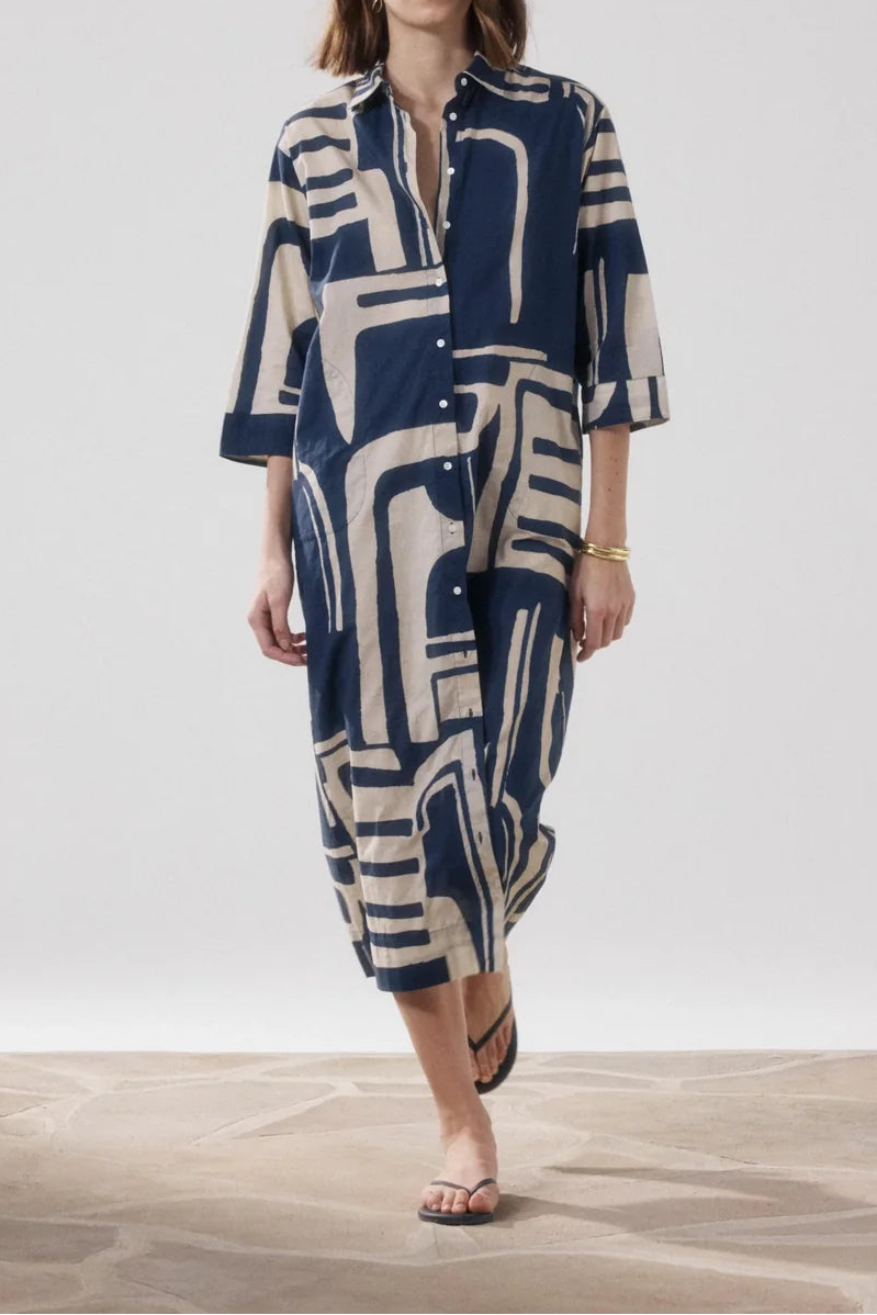 Woman wearing a blue and beige patterned dress on a plain background