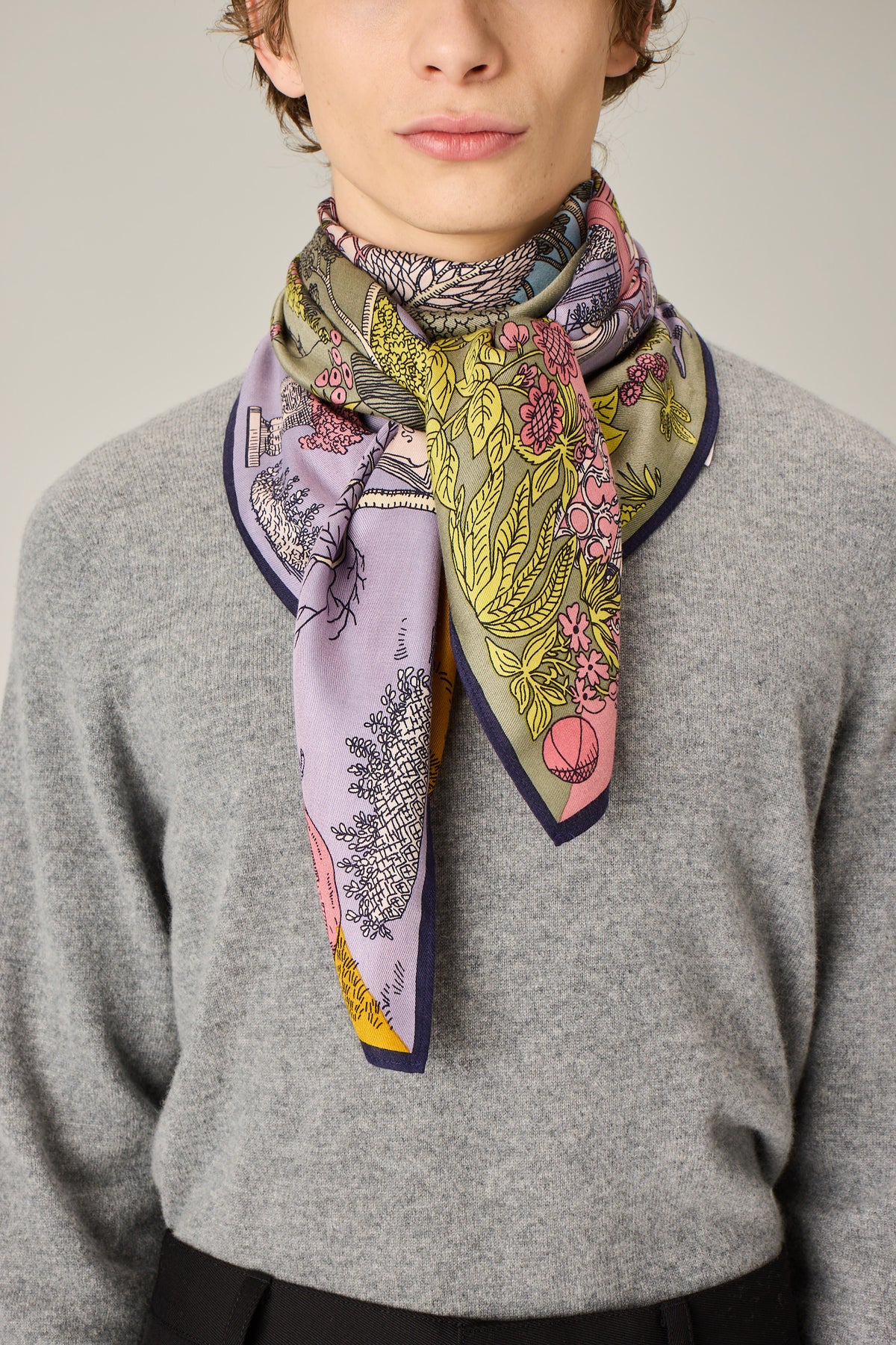 Person wearing a colorful patterned scarf on a plain background