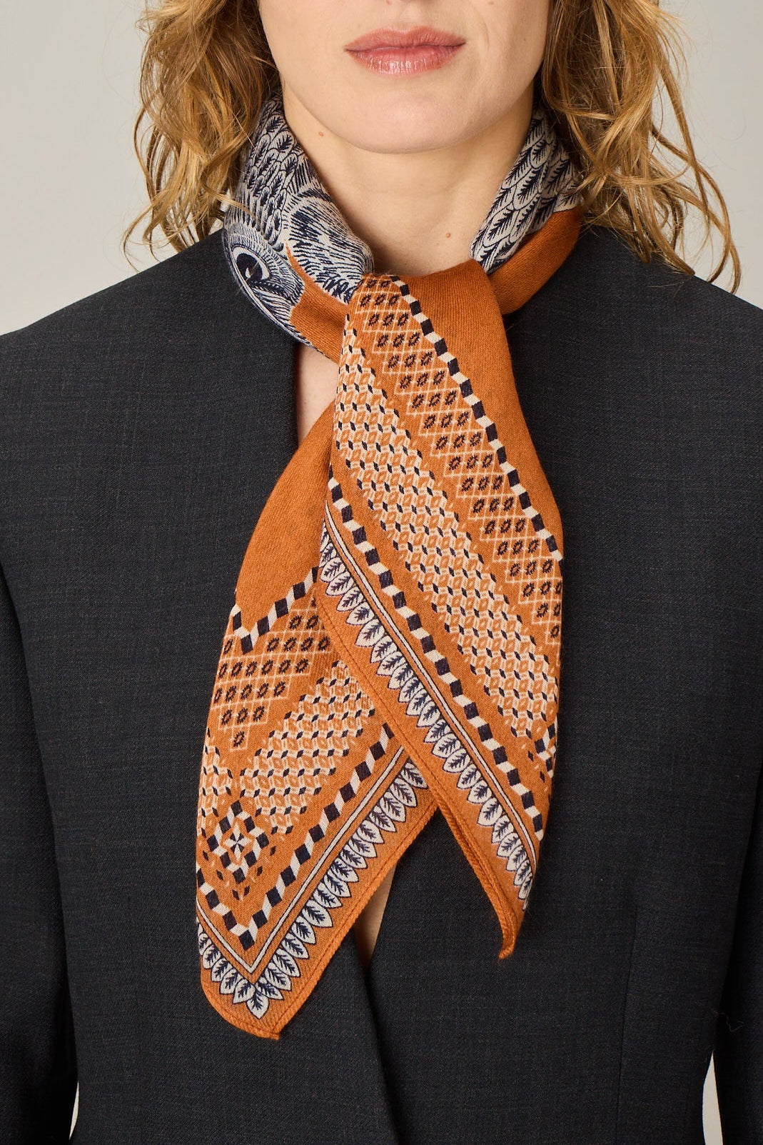 Woman wearing a patterned scarf on a plain background