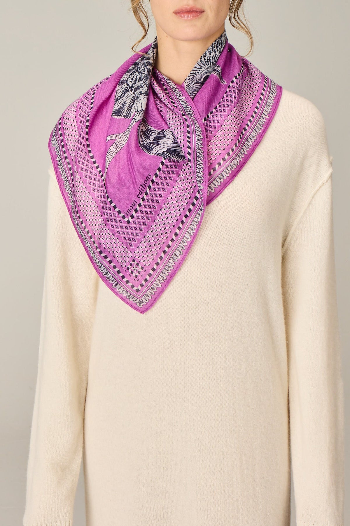 Woman wearing a purple scarf with a pattern on a plain background