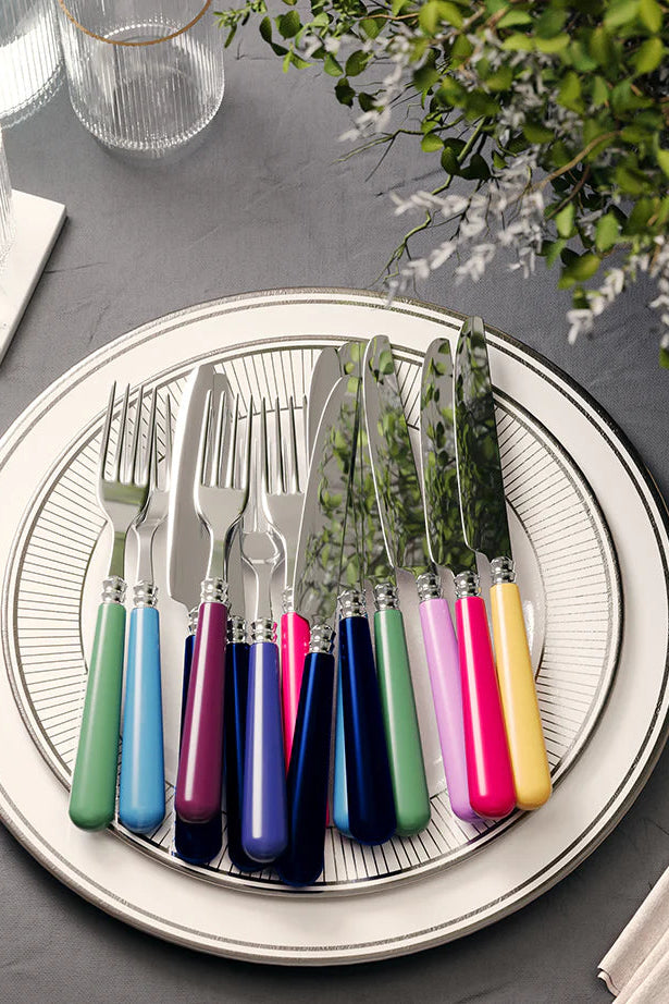 Colorful cutlery set on a round plate with a gray background