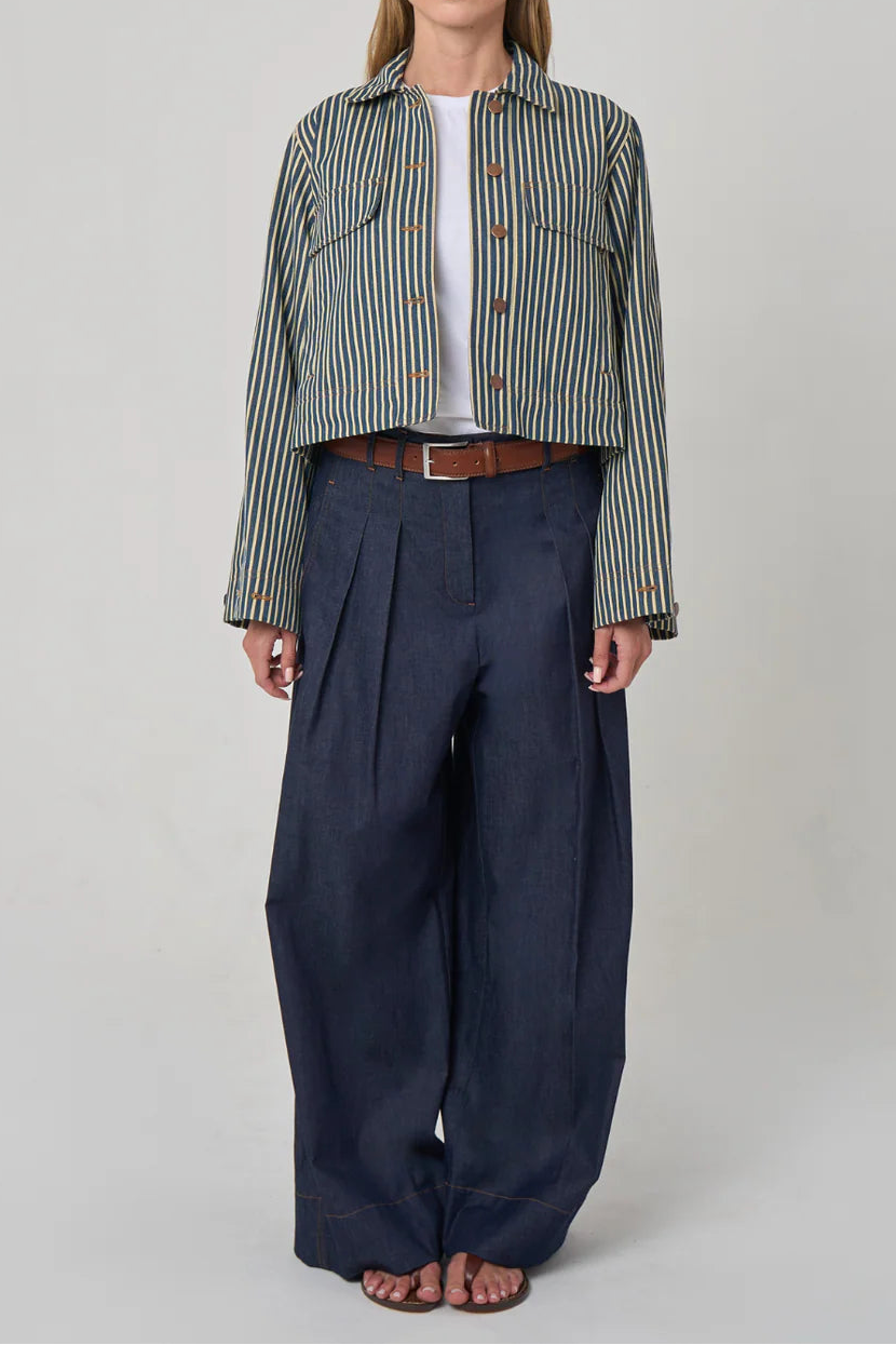 Woman wearing a striped shirt and wide-leg pants on a plain background
