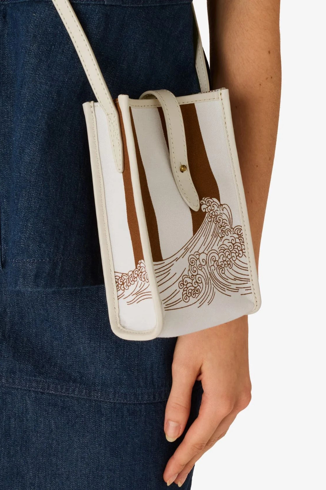 Handbag with wave design held by a person wearing a blue apron