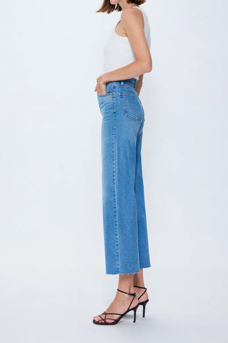 Woman wearing a white top and blue jeans on a white background