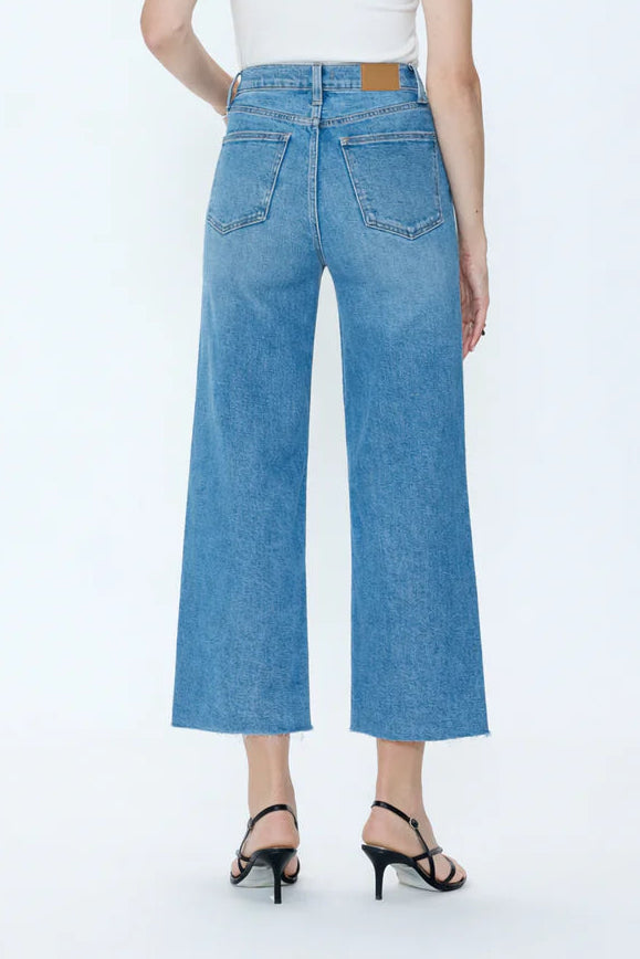 Woman wearing blue jeans and a white top on a white background