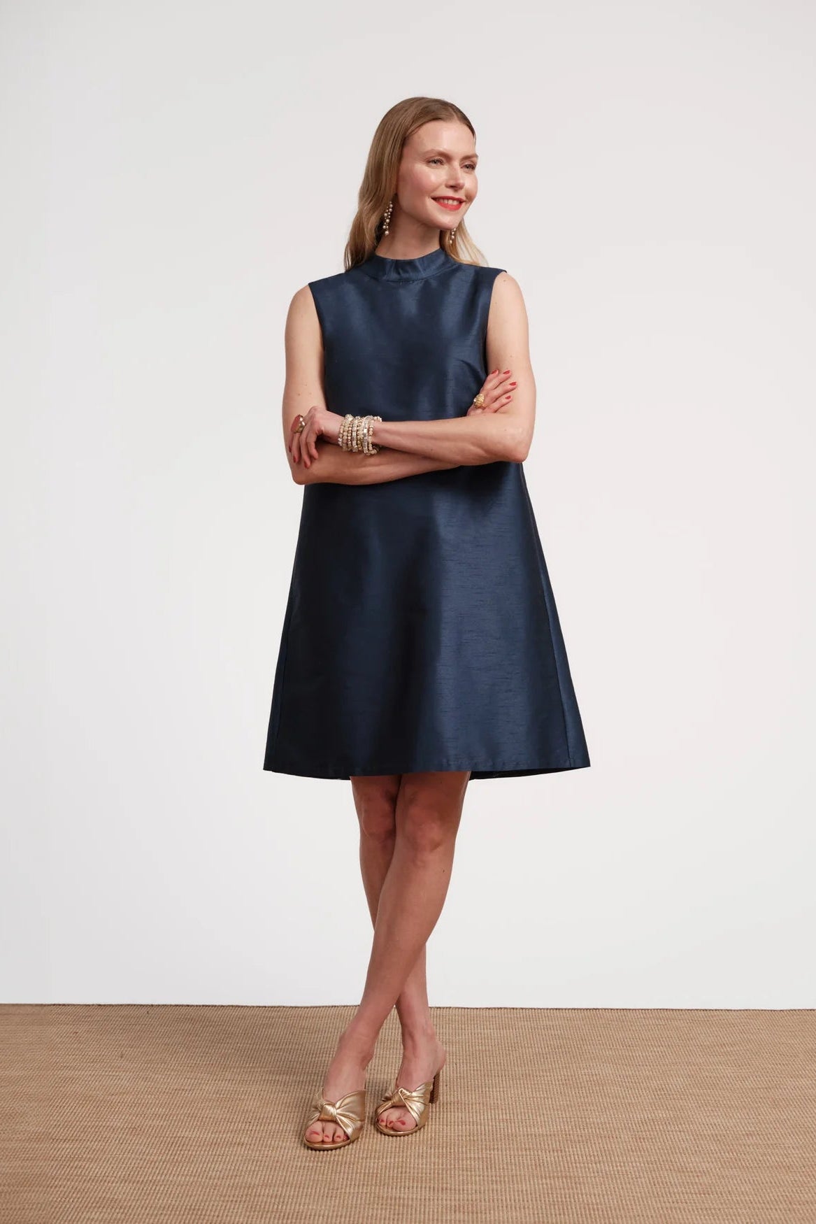 Woman wearing a navy blue sleeveless dress on a plain background