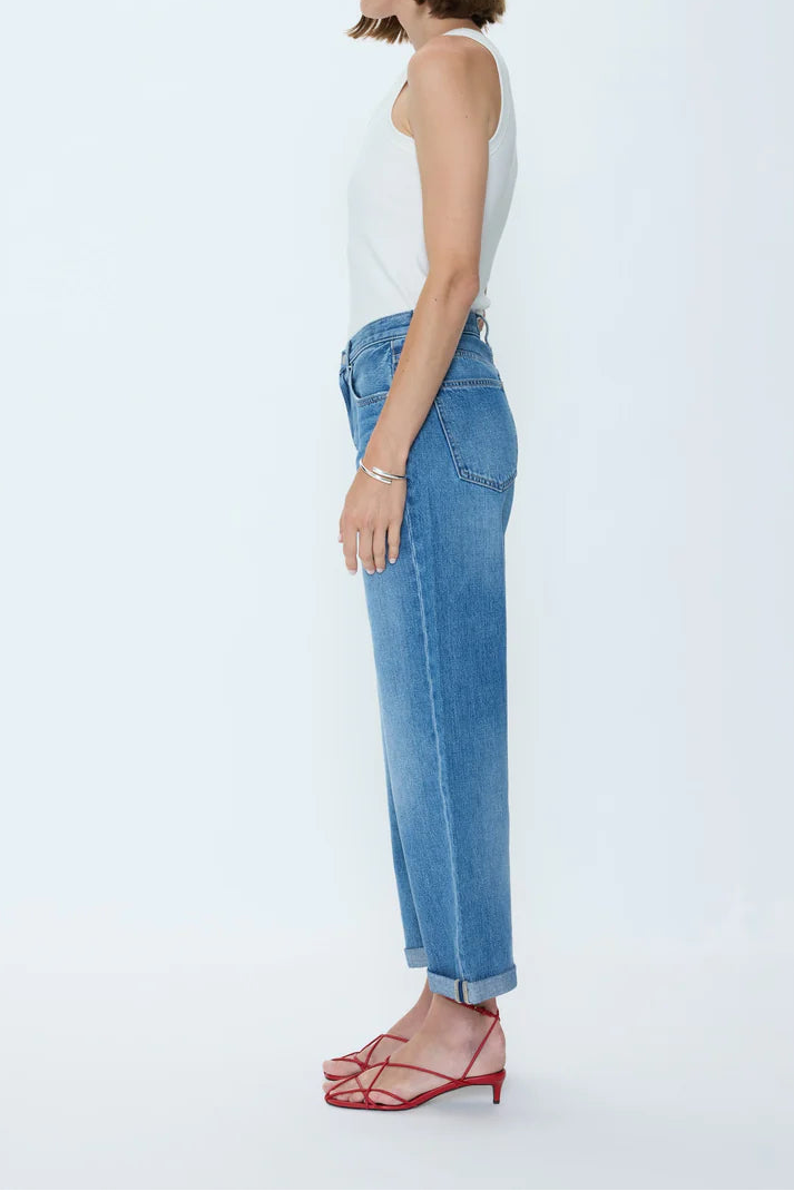Woman wearing a white top and blue jeans on a white background