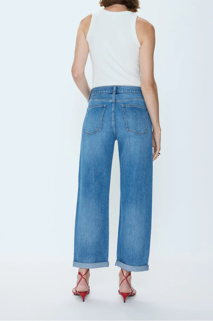 Woman wearing blue jeans and a white top on a white background