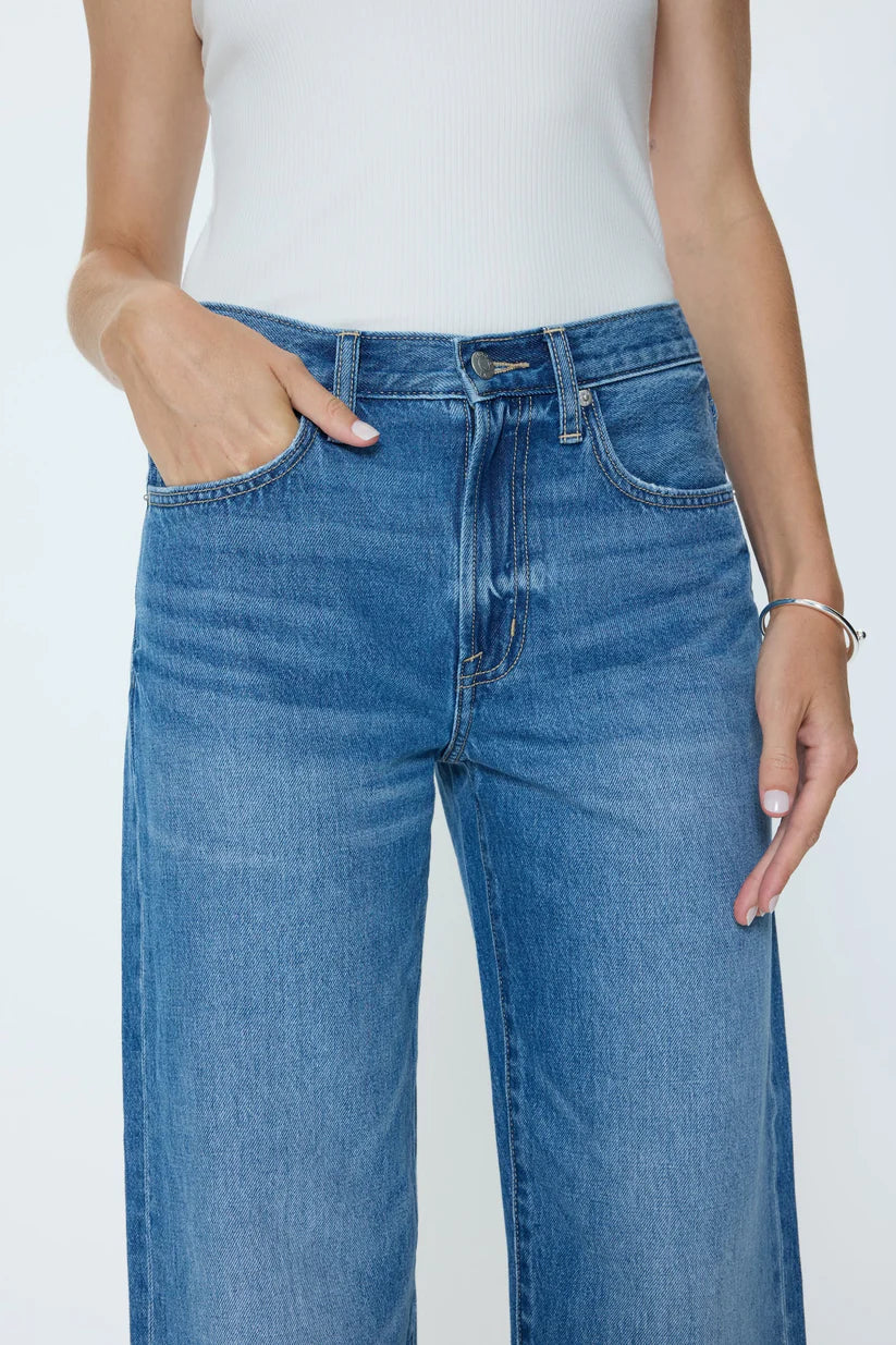 Person wearing blue jeans with a plain background