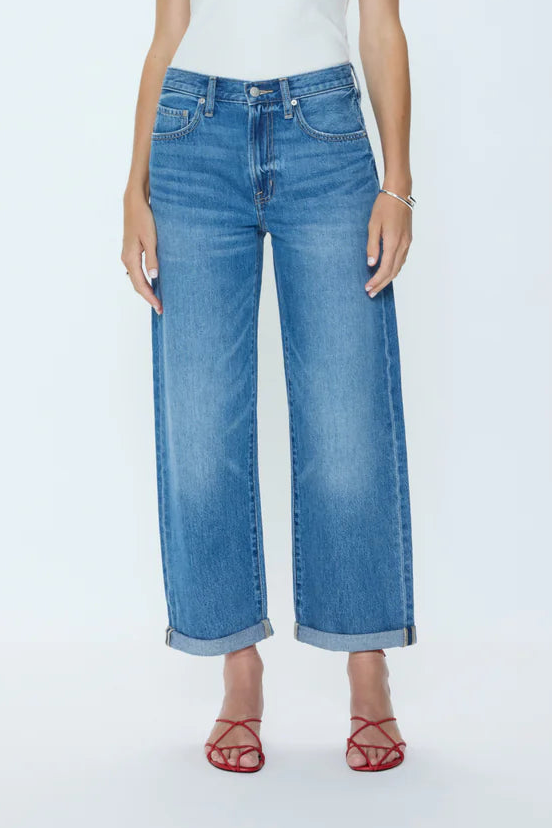 Woman wearing a white tank top and blue jeans on a white background