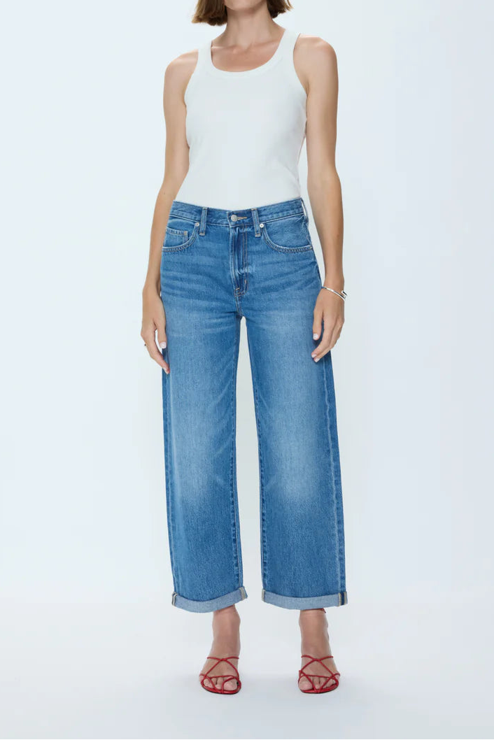 Woman wearing a white tank top and blue jeans on a white background