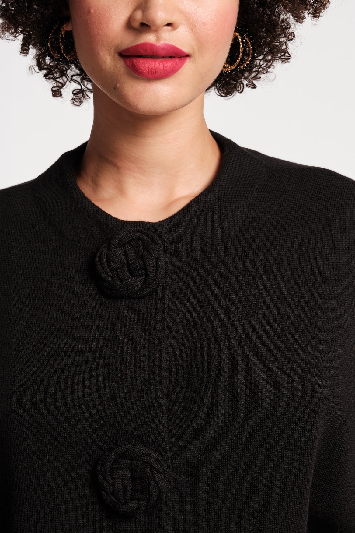 Close-up of a person wearing a black coat with a plain background