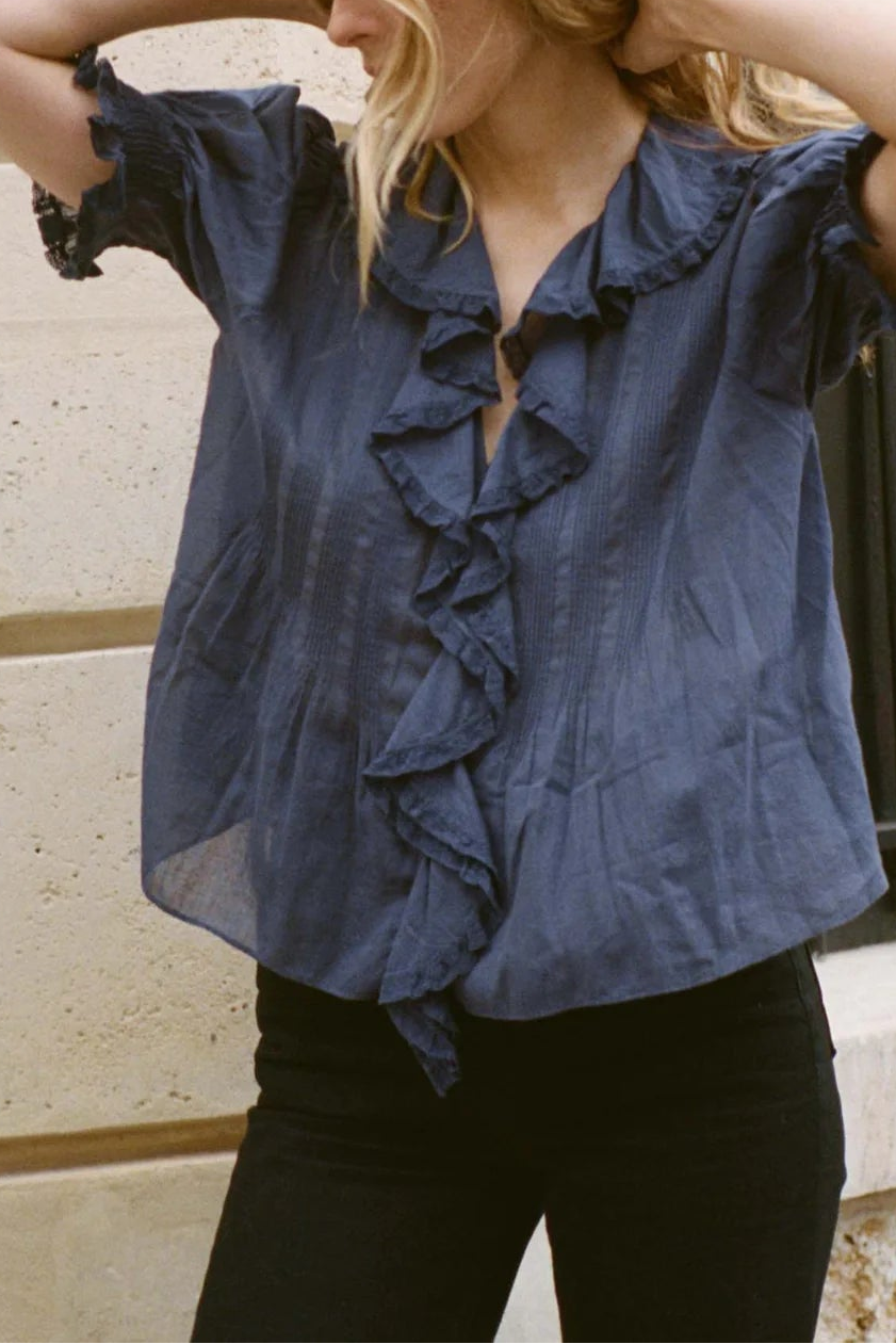 Woman wearing a blue blouse with ruffles in an urban setting