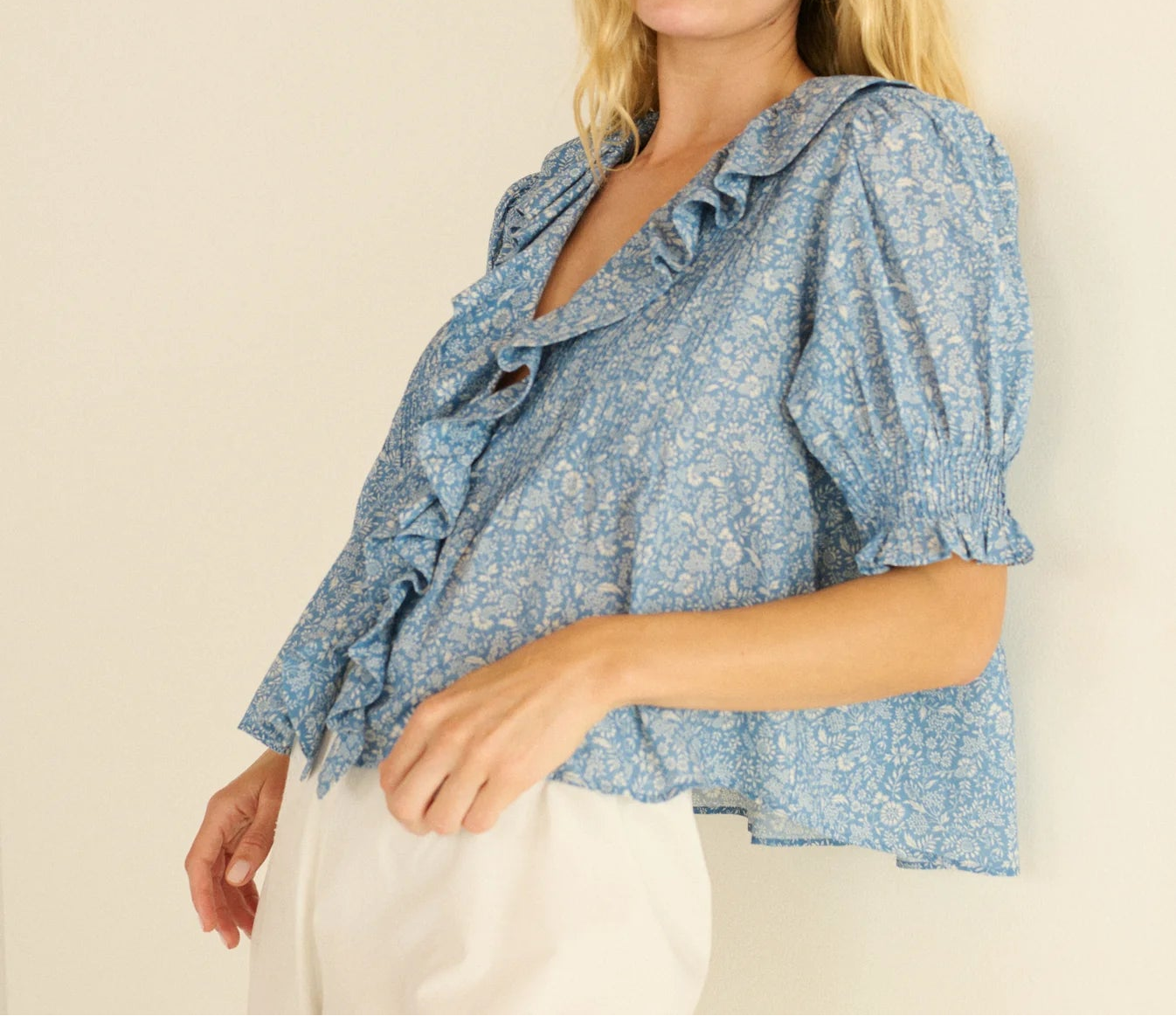 Woman wearing a blue floral blouse against a plain background