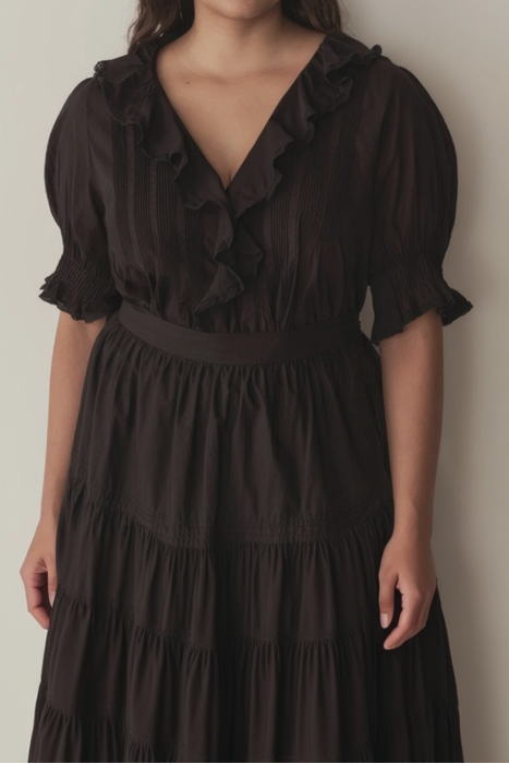 Woman wearing a black dress with ruffled details against a plain background
