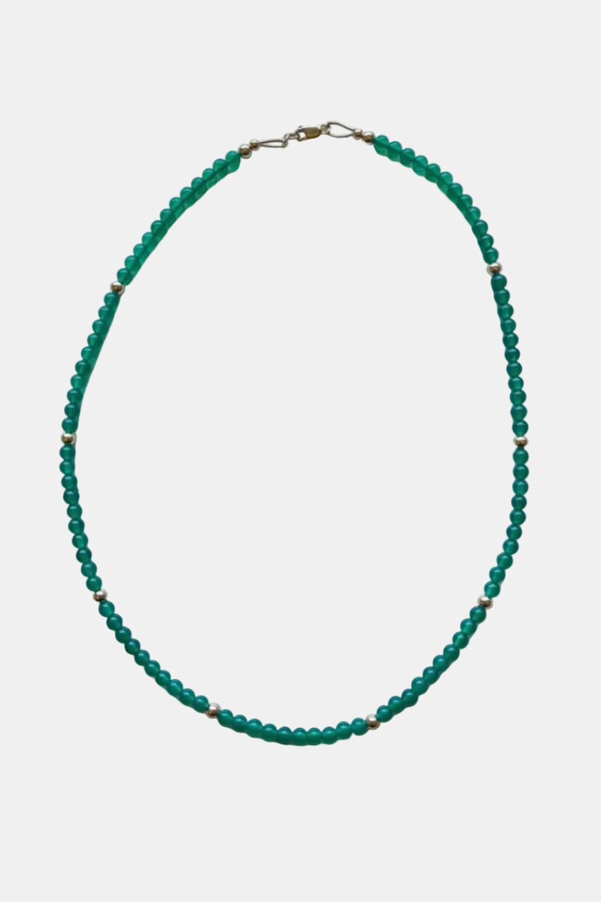Green beaded necklace on a marble surface
