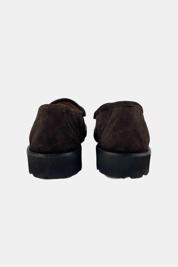A pair of dark brown suede slip-on shoes viewed from the back, featuring thick black platform soles, set against a plain white background.