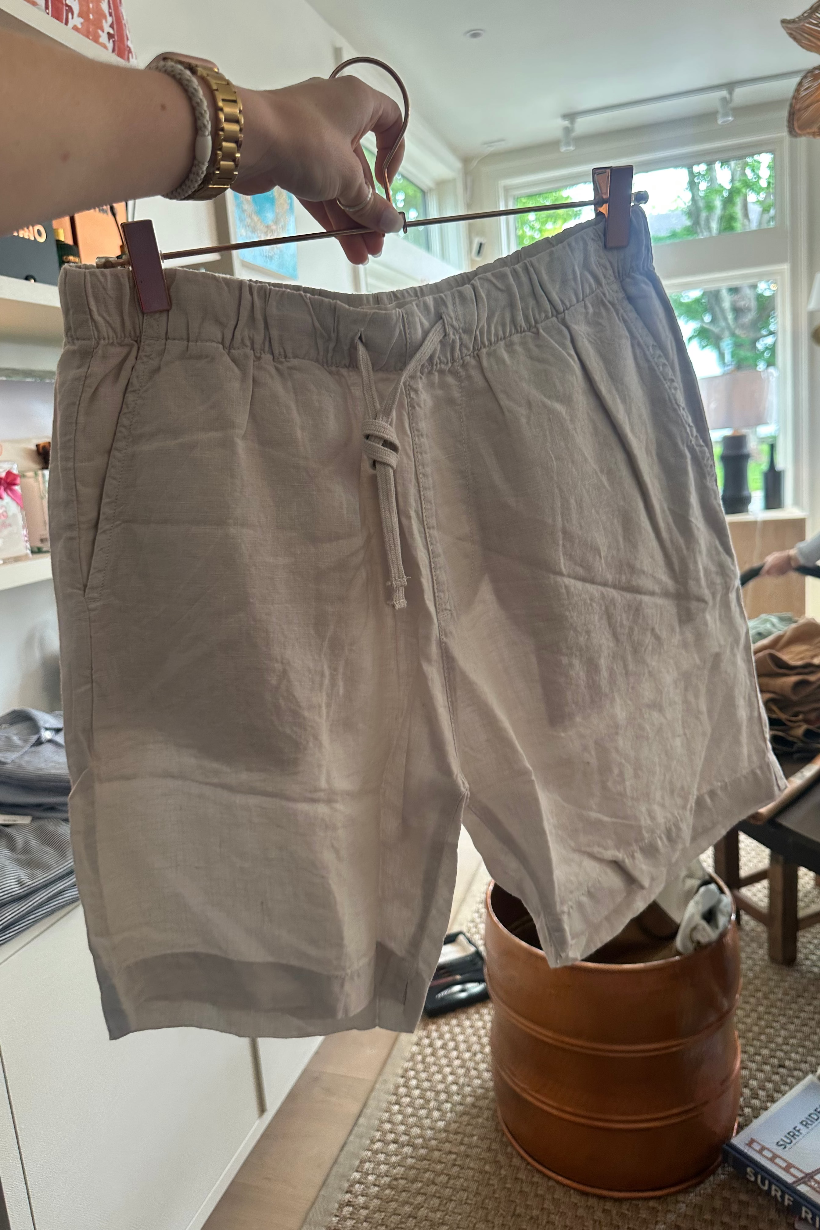 Beige shorts hanging on a hanger in a room with furniture and decor.