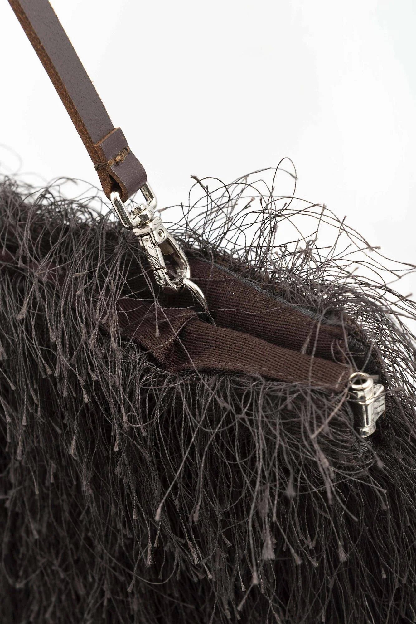 Close-up of a brown leather strap with metal hardware on a textured surface.