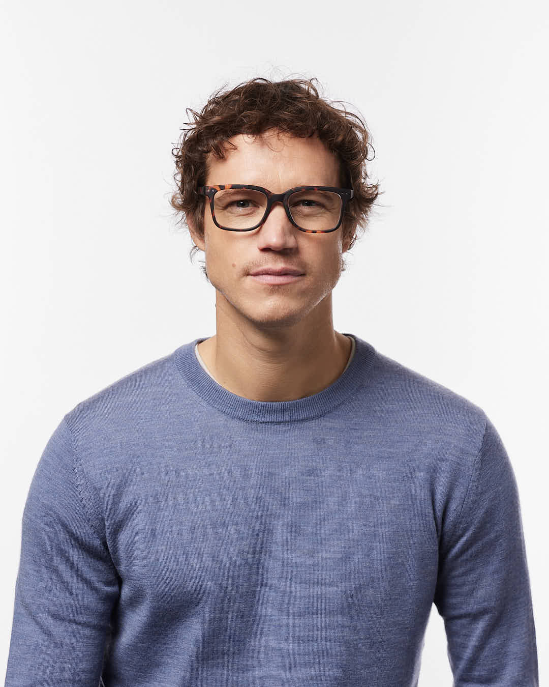 Man wearing glasses and a blue sweater on a white background